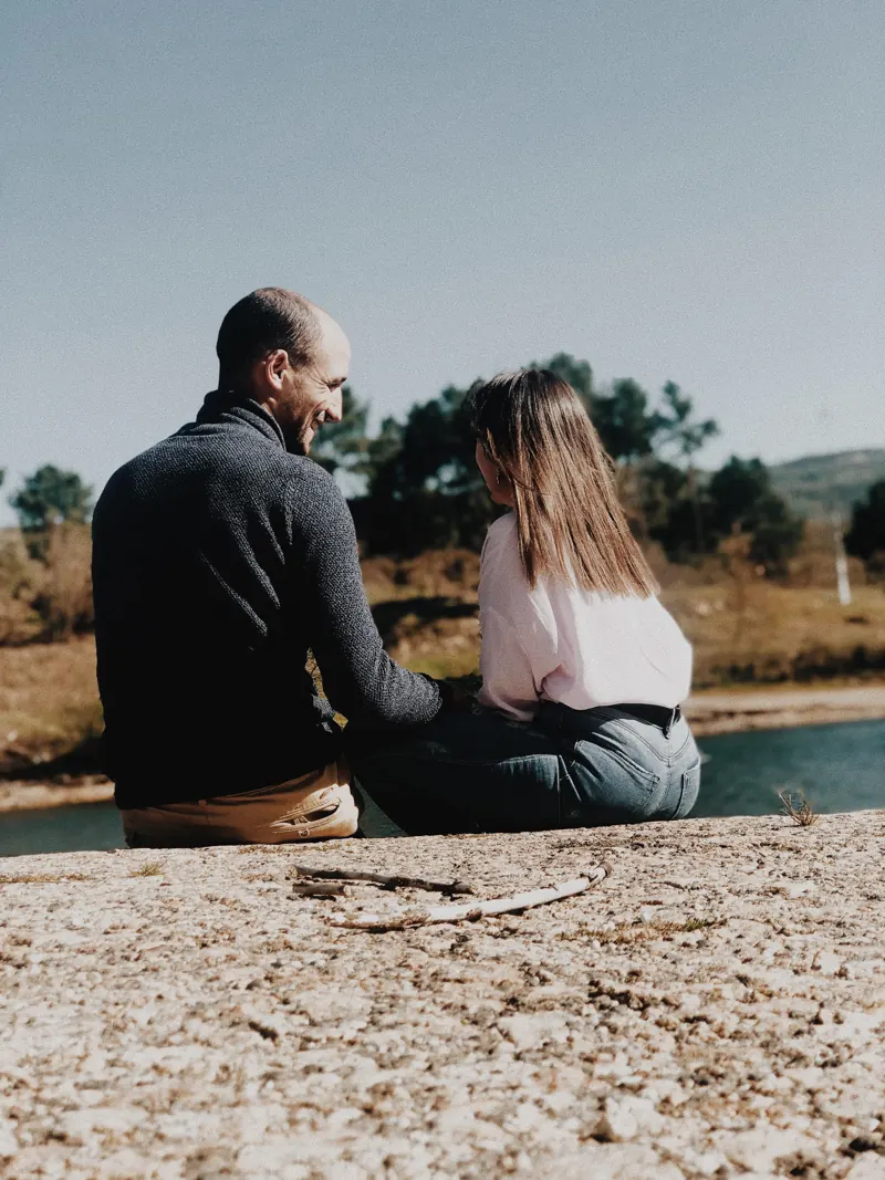 O casal sentado junto a um lago