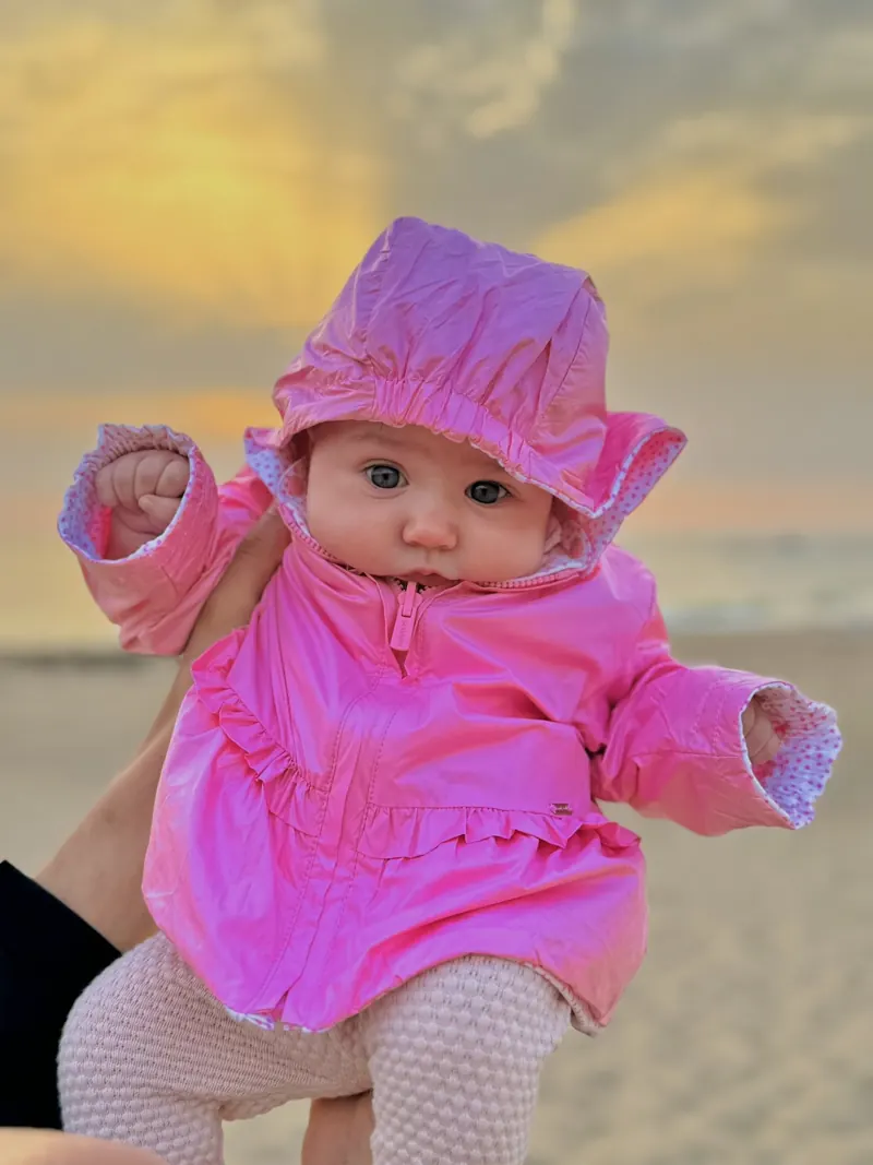 Margarida na praia com casaco cor-de-rosa